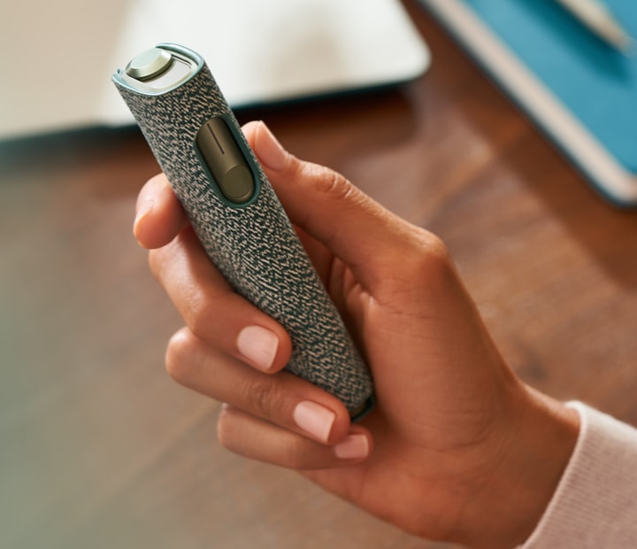 An IQOS ILUMA ONE devices in a persons hand. An IQOS ILUMA ONE devices in a persons hand.