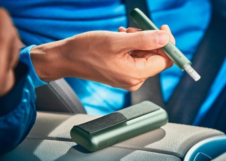 Close up of a hand holding a jade green IQOS ILUMA device. Close up of a hand holding a jade green IQOS ILUMA device.