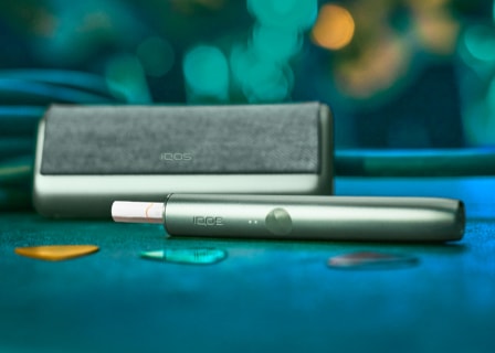 A jade green IQOS ILUMA device and charger A jade green IQOS ILUMA device and charger