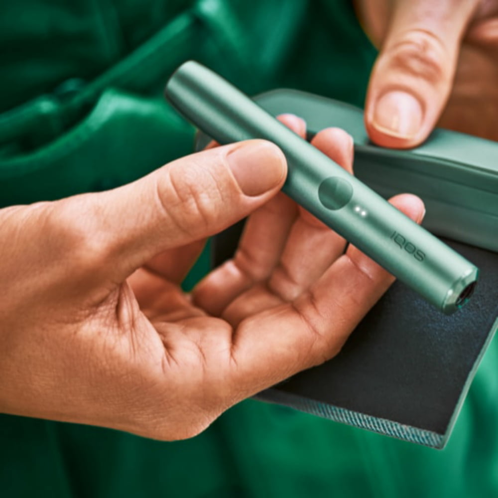 An IQOS ILUMA PRIME Holder in a persons hands, the lights visibile.  An IQOS ILUMA PRIME Holder in a persons hands, the lights visibile.