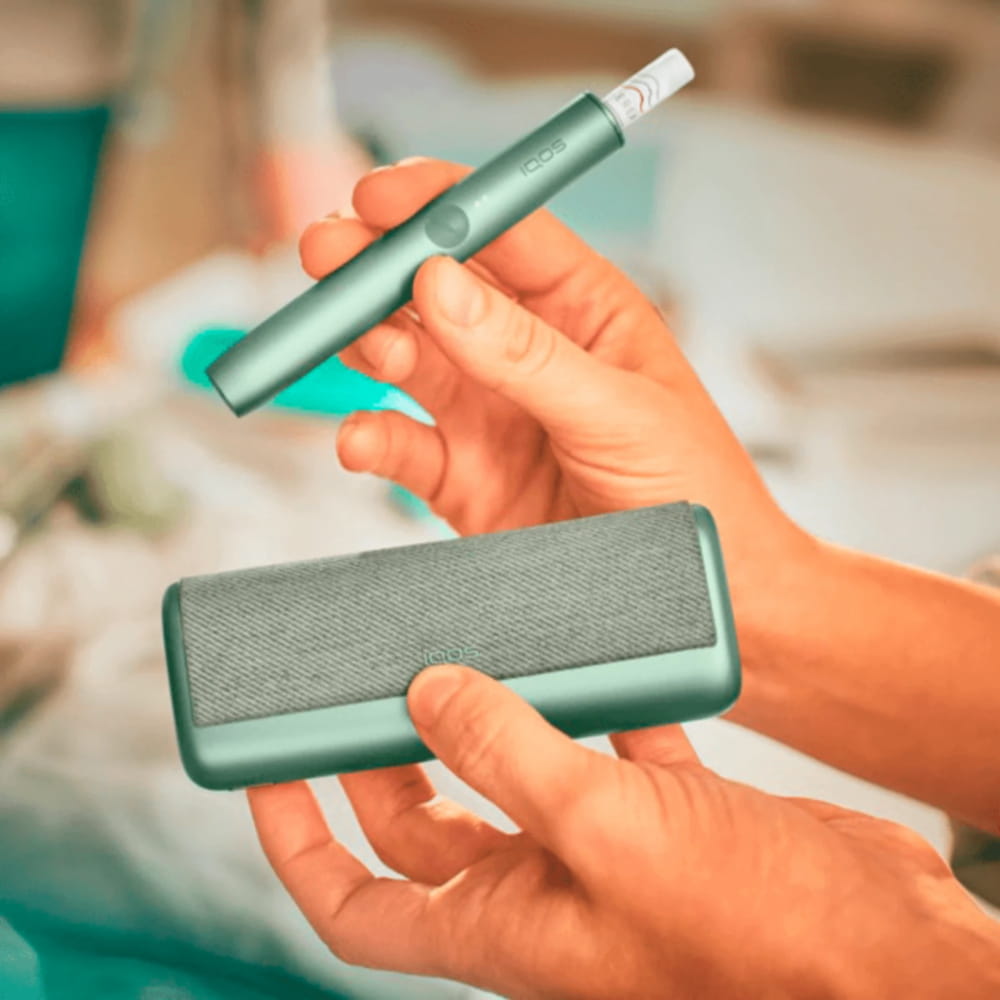 جهاز IQOS ILUMA PRIME أخضر زمرّدي وشاحنه في يد. جهاز IQOS ILUMA PRIME أخضر زمرّدي وشاحنه في يد.