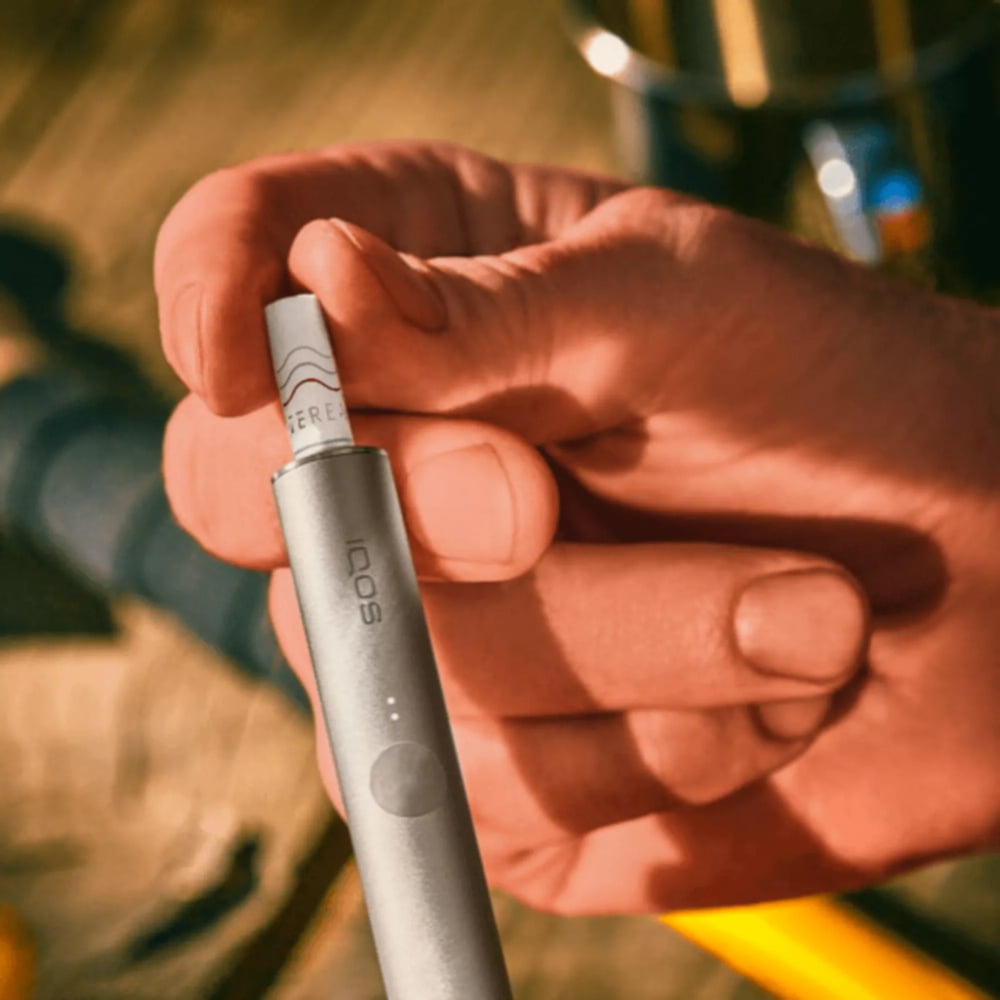 A person places a TEREA stick into an IQOS ILUMA PRIME Holder.  A person places a TEREA stick into an IQOS ILUMA PRIME Holder.