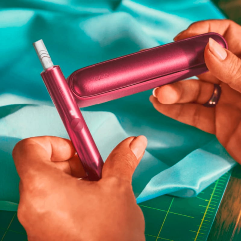 A bright IQOS ILUMA Pocket Charger and Holder in a persons hand. 