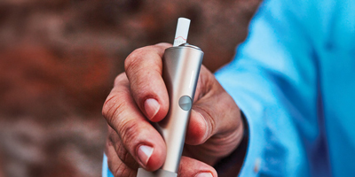 Two people holding phones over two cups of coffee.