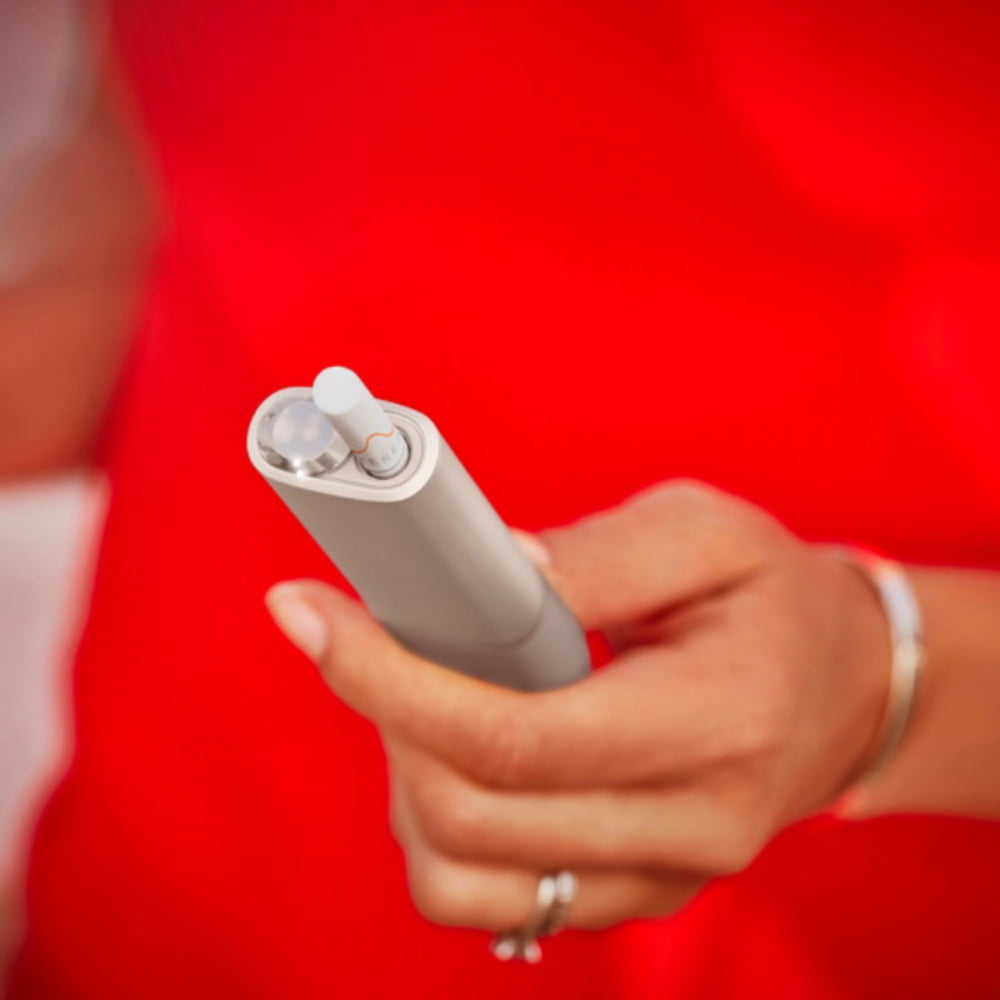 A person holding an IQOS ILUMA ONE.