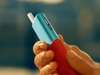 يد تمسك بجهاز IQOS ILUMA i ONE باللون الأزرق السماوي