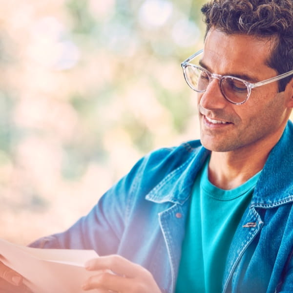 A man wearing glasses reading a warranty brochure.