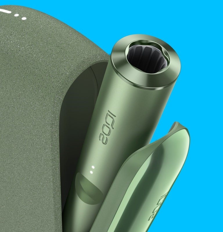 جهاز IQOS ILUMA باللون الأخضر الطحلبيّ داخل شاحن الجيب بغطاء مفتوح.