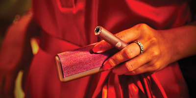 A passport, plane ticket, and IQOS device on a desk.