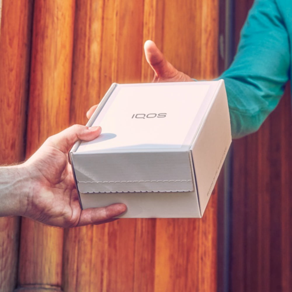 Someone handing over an IQOS box.