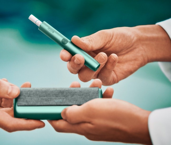 Close up of hands sharing an IQOS ILUMA device.