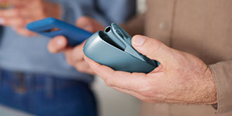 a man holding an iqos original duo