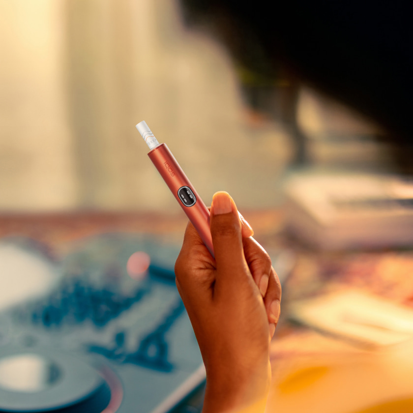 An IQOS ILUMA PRIME Holder in a persons hands, the lights visibile. 