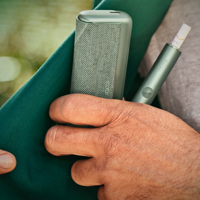 Close up of hand taking IQOS ILUMA device from pocket.