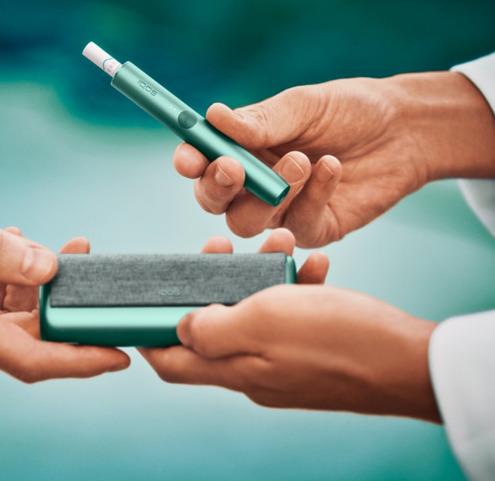 لقطة مقربة لأيدٍ تتشارك جهاز IQOS ILUMA.