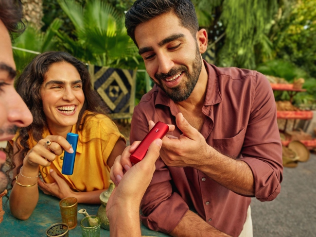 Hand putting a red BONDS by IQOS device in jeans pocket
